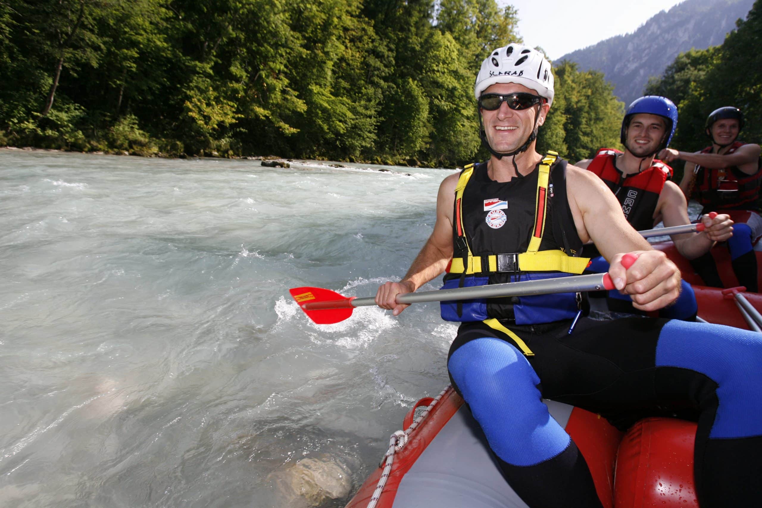 Rafting in einem Schlauchboot auf dem Fluss, vorbei an einer malerischen Bergkulisse.